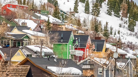 Panorama frame Houses with colorful walls built on a mountain covered with snow in winter. Lush coniferous trees can also be seen under the cloudy gray sky.の写真素材