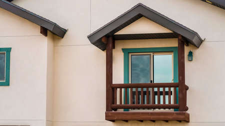 Panorama Small balcony with brown wooden railings and posts under a pitched roof. A shiny sliding...