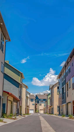 Vertical frame Rows of houses with paved road in the middle under blue sky on a sunny day. Garage...