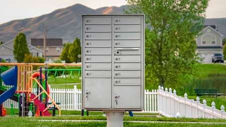 Panorama White metal cluster mailbox on the sidewalk in front of a colorful playgroundの写真素材