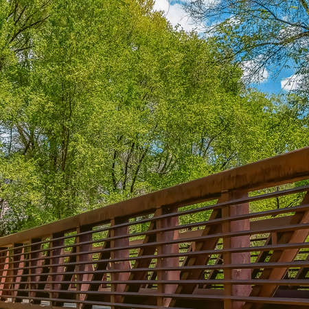 Square frame Bridge with latticed metal guardrail over a calm stream viewed on a sunny dayの写真素材