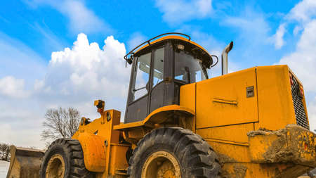 Panorama frame Close up of a dirty yellow loader with black rubber wheels and empty cab