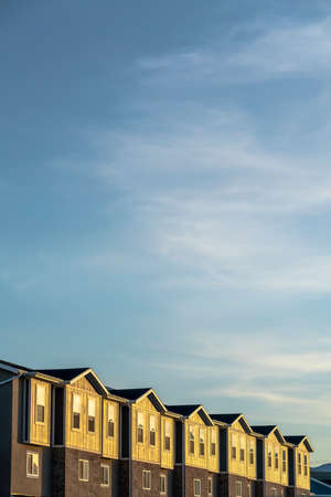 Townhouses on a neighborhood under blue sky and clouds on a sunny dayの写真素材