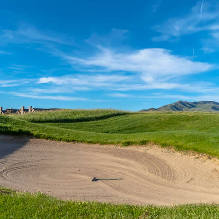 Square Golf course with sand bunker and vibrant fairway under blue sky on a sunny dayの写真素材