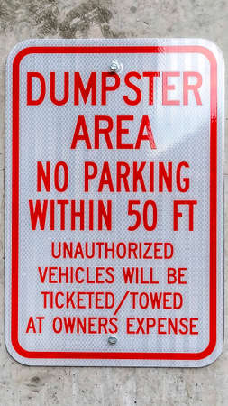 Vertical Close up of a sign that reads Dumpster Area No Parking against a concrete wallの写真素材