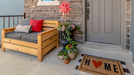 Panorama Porch of a home decorated with wooden chair potted plants wreath and doormatの写真素材