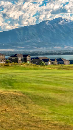 Vertical Residential area near a lake with an expansive grassy terrain in the foregroundの写真素材