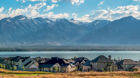 Panorama frame Picturesque landscape with homes overlooking a blue lake and towering mountainの写真素材