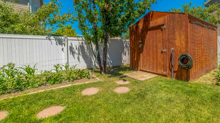 Panorama Small wooden shed at the garden of a home against blue sky on a sunny dayの写真素材
