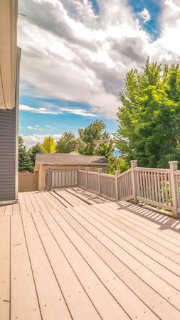 Vertical frame Spacious balcony of home with view of trees and cloudy blue sky on a sunny day. The...