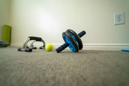 Close up of an ab wheel and push up bar on the floor of a workout fitness room. Gym and exercise...