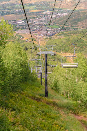 Chairlifts overlooking trails and buildings at a ski resort during off seasonの写真素材