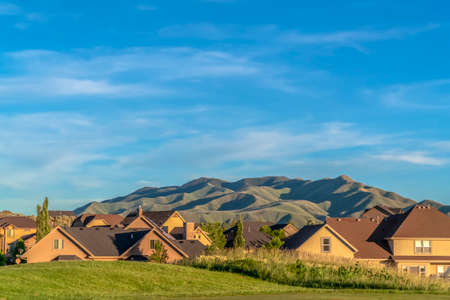 Golfing area overlooking a scenic view of houses and mountain against blue skyの写真素材