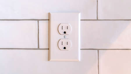 Panorama frame Power outlet on white wall in home. Double Type B electrical socket AC power outlet placed vertically on white wall decorated with brick tiles in close-upの写真素材