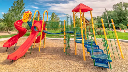 Panorama frame Bright colorful childrens playground under blue sky and clouds on a sunny day. Scenic...