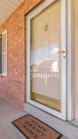 Vertical Front door of suburban brick home with welcome mat. The front porch and door of a traditional suburban brick home with a welcome mat.の写真素材