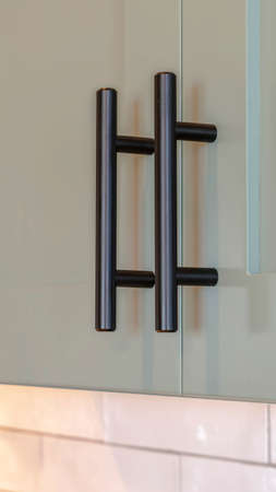 Vertical frame Close up of overhead kitchen cupboards and handles. A close up of overhead kitchen cupboards with black handles.の写真素材