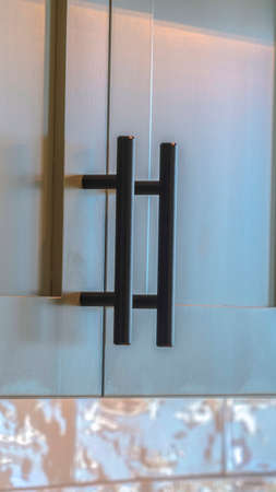 Vertical frame Close up of modern kitchen cupboards and handles. A close up of modern overhead, green kitchen cupboards and black handles.の写真素材