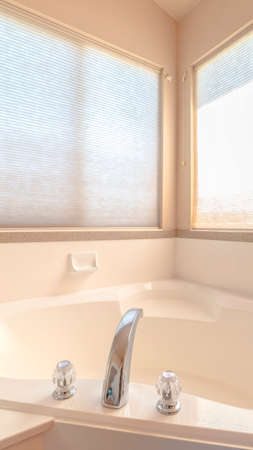 Vertical frame Luxurious bath tub with bright, warm window light. The interior of a bathroom with a...
