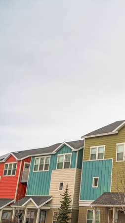 Vertical frame Townhomes with colorful exterior walls and front porches against cloudy skyの写真素材