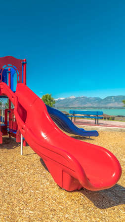 Vertical frame Focus on slides at a park with view of lake and distant timapanogos mountainsの写真素材