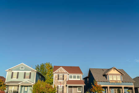 Row of three houses on a modern urban estate. Row of three houses on a modern urban housing estate with trees in the gardens. A low angle view of the facades in evening lightの写真素材