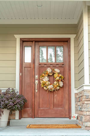 Front door with dried flower wreath day. Wooden front door with dried flower to a residential...