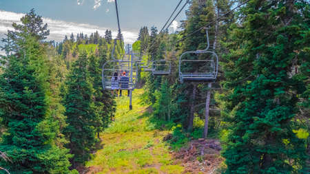 Panorama frame Chairlift with tourists over hiking trail in Park City mountain at off season. Scenic...