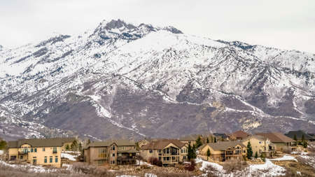 Panorama frame Winter landscape with homes on a hill overlooking a striking snowy mountain