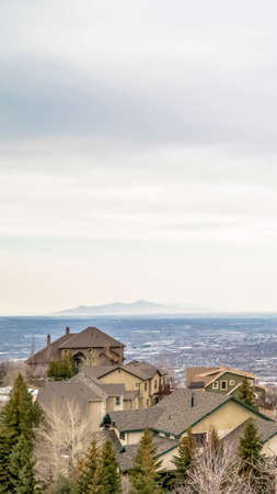 Vertical Aerial view of houses in the valley with mountain and horizon in the distanceの写真素材