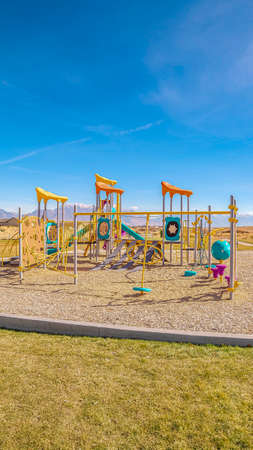 Vertical frame Colorful equipment in a kids playground during day. Colorful equipment in a kids playground set in neat maintained lawns in a residential neighbourhoodの写真素材