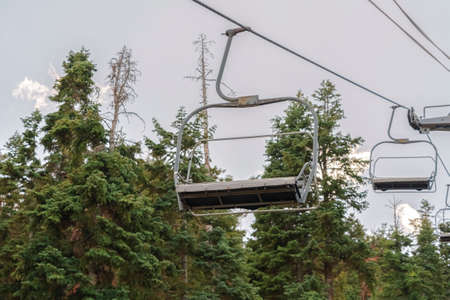 Chairlifts against conifers and cloudy sky in Park City ski resort at off seasonの写真素材
