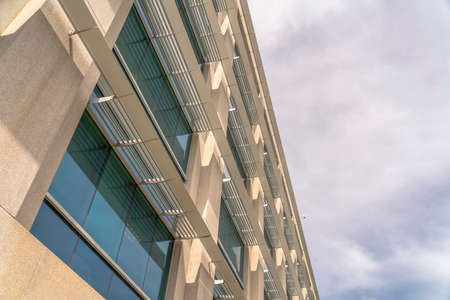 Modern office building exterior viewed against cloudy sky on a sunny day