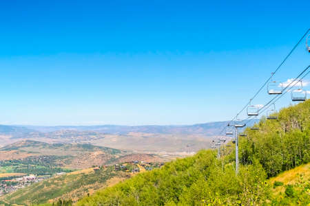Park City during off season with chairlifts over green trees and mountain view