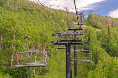 Chairlifts on cables over ski mountain with thick green trees during off season