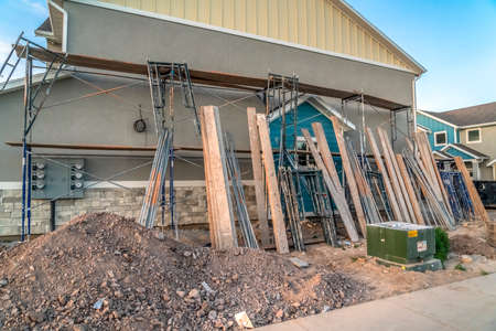Residential construction with scaffolding and wooden beams against wall of home. Construction...