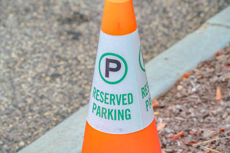 Traffic cone with Reserved Parking sign standing alongside a white line marking on asphaltの写真素材
