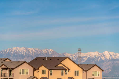 Exterior of homes with beige walls and balcony against snow capped mountainの写真素材