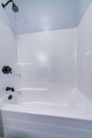Modern interior fitted white tiled shower cubicle with deep tub and mixer taps in closeupの写真素材