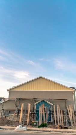 House exterior with construction materials against wall on blue sky background. The house has gable...