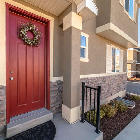 Square Colourful red entrance door to a house with wreath in a modern urban housing development