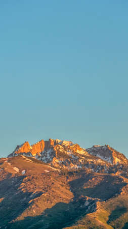 Vertical Scenic view of a mountain peak with rugged slopes and dusted with snowの写真素材