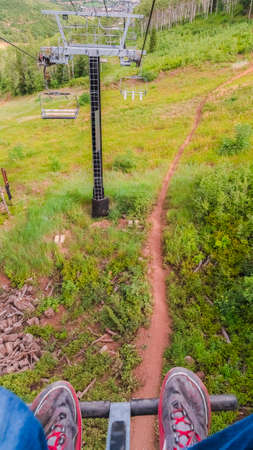 Vertical frame Man on chairlift overlooking mountain and trails in Park City Utah at off season....