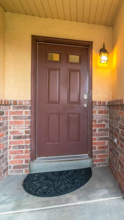 Vertical Brown door with glass panels of a home with concrete and brick exterior wall. A sliding...