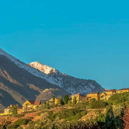 Square Houses on a hill with view of snowy mountain and cloudless blue skyの写真素材