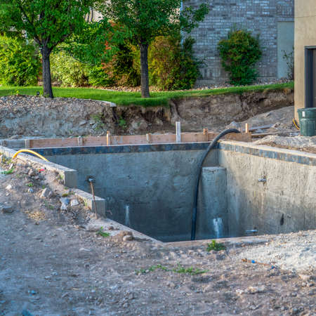 Square frame Construction of a residential swimming pool with houses and trees background