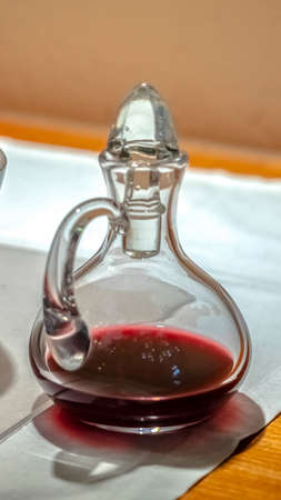 Vertical frame Glass carafe with red communion wine symbolising the blood of christ on a table in a...