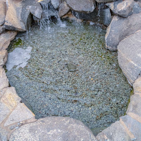 Square Stone cascade waterfall outdoor landscape design decoration with small round pool, viewed...