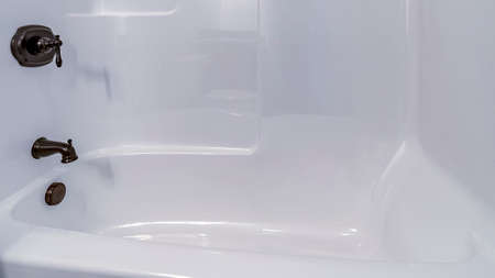 Panorama Modern interior fitted white tiled shower cubicle with deep tub and mixer taps in closeup