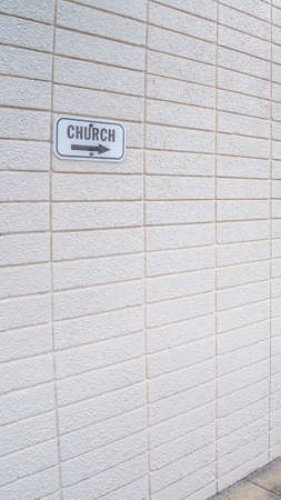 Vertical frame Covered entrance door in a modern white building viewed at a corner angle with church sign and arrowの写真素材